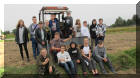 Grupa uczniów stojąca przy traktorze na polu 